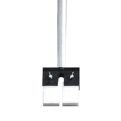 Close-up view of the base of a metal pole secured by a clamp above two white blocks on the floor with partial view of a persons feet in the background.