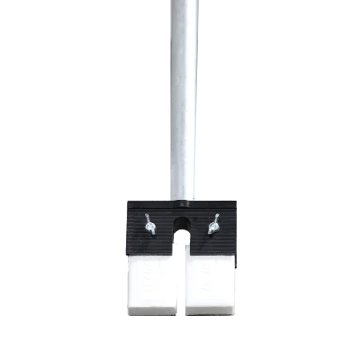 Close-up view of the base of a metal pole secured by a clamp above two white blocks on the floor with partial view of a persons feet in the background.